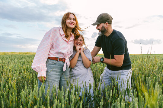 Happy family stands together in a green wheat field during summer