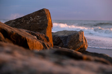 Large coastal rocks at sunset with ocean waves breaking on the shore © Maria