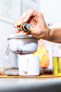 Hand dripping essential oil from a bottle into a diffuser for aromatherapy session