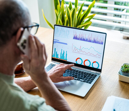 Man analyzing data on laptop while calling in the office