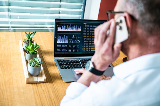 Broker analyzing finance data on notebook while calling in office