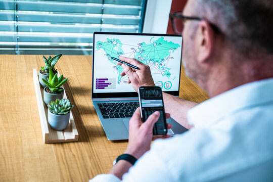 Businessman analyzing global data on laptop and mobile phone