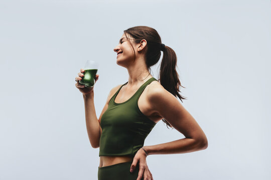 Woman in studio drinking healthy detox drink and smiling