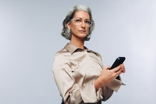 Mature businesswoman using smartphone in studio