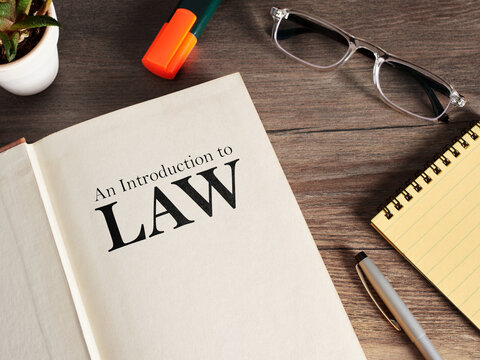 Studying law with open textbook and reading glasses. Introduction to law textbook.