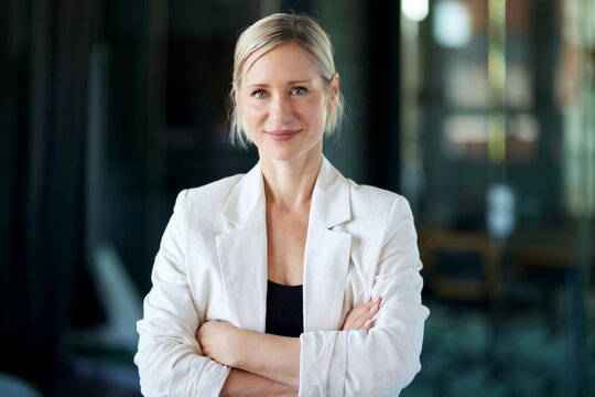 Confident businesswoman stands with crossed arms in the office