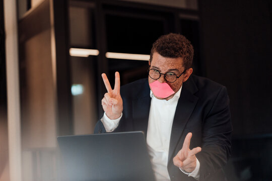 Man with sticky note lip makes peace sign during online meeting