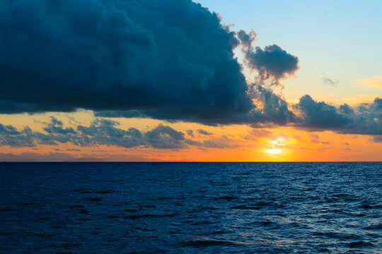 Dramatic sunset over the ocean with dark clouds and vibrant sky