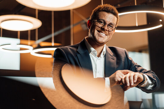 Smiling businessman checks his smartwatch in a modern office