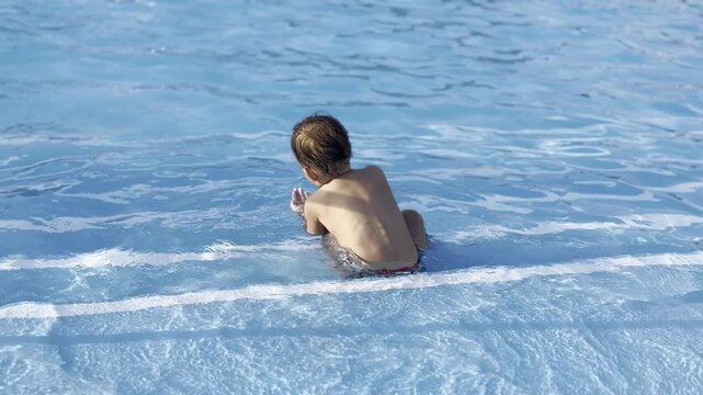 Young child sitting in shallow swimming pool