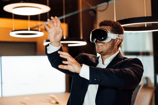 Businessman wearing VR glasses touches virtual objects in office