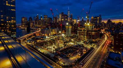 Fototapeta premium Cityscape with Active Construction Cranes and Infrastructure Growth at Twilight