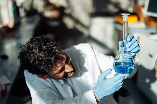 Scientist examining blue liquid in a laboratory flask