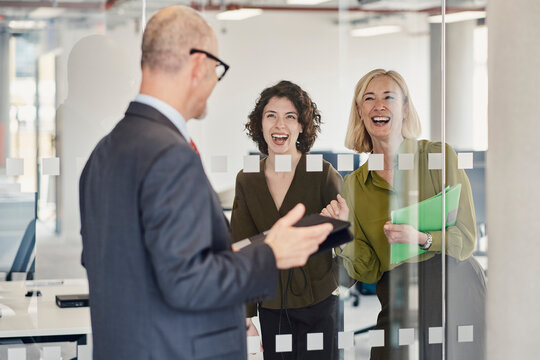 Businessman talks to smiling female colleagues in London office