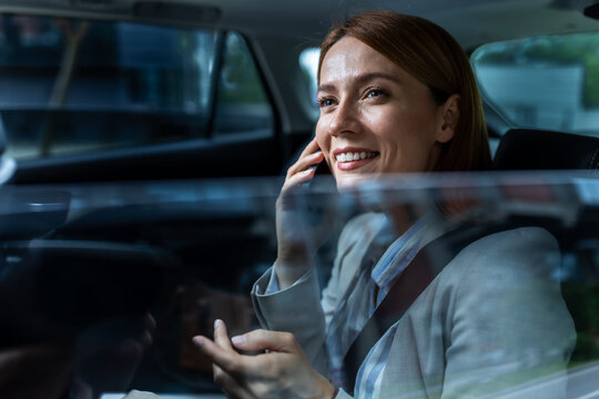 Woman talking on phone on the back seat of the car