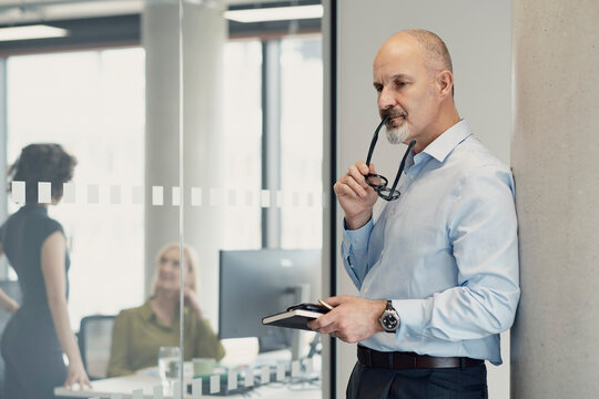 Thoughtful businessman holds eyewear in a modern London office