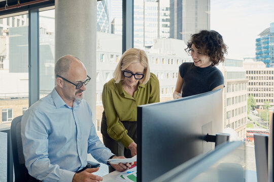 Business colleagues review papers at a modern London office desk