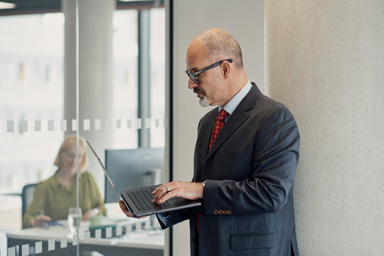 Businessman types on laptop in London office with woman