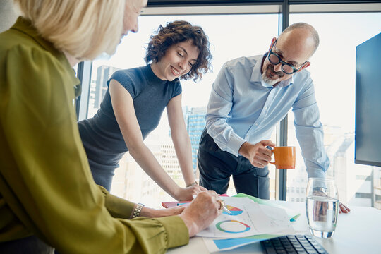 Colleagues discuss business strategy at an office desk in London