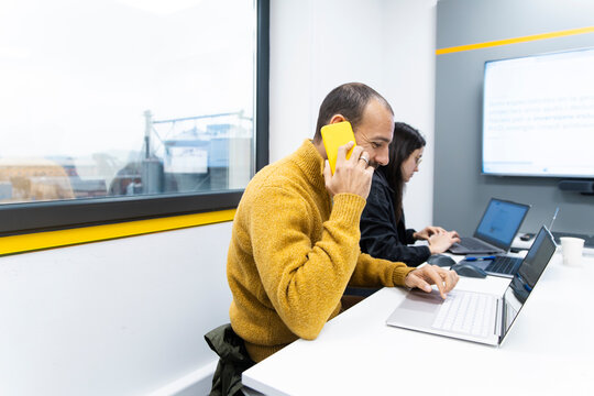 Businessman multitasks with smartphone and laptop in the office
