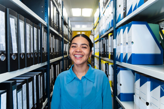 A happy businesswoman organizes documents in an office archive
