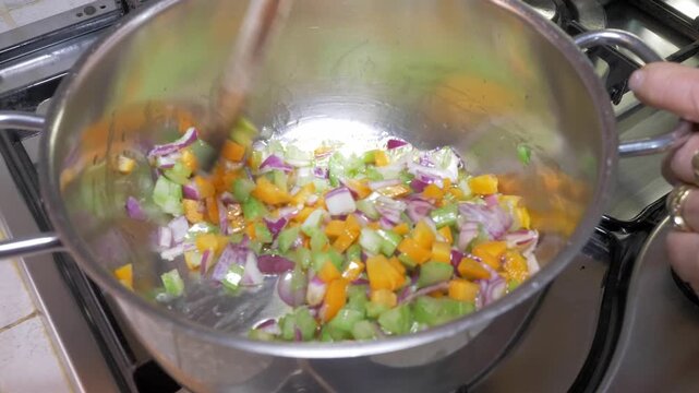 Celery, carrots and onion soffritto gently cook together in a pot, their colors softening and blending as they release their rich aromas in this essential Italian cooking base.