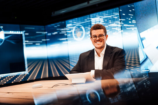 Smiling man presents news in a modern television studio