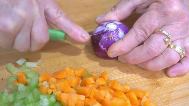 Knife Slicing Fresh Carrot on Wooden Cutting Board, Soffritto Preparation. Vibrant Orange Carrot Being Sliced on Board for Italian Soffritto Base