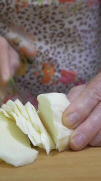 Vertical: An extreme close-up captures the precise moment a knife cuts through scamorza cheese, highlighting its smooth surface and the careful preparation that goes into every homemade Italian meal.