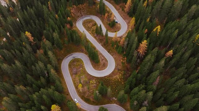 Giau Pass snake road in Italy, aerial top view of beautiful nature with bunch of green and yellow trees.
