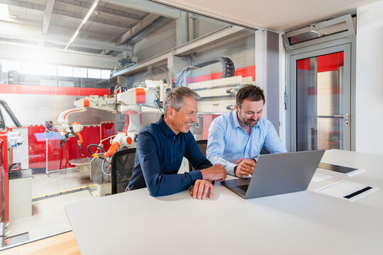 Businessman and engineer use a laptop in a modern factory office