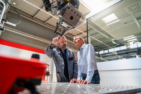 Manager and engineer inspect an industrial robot in a factory
