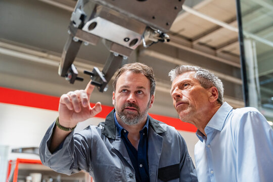 Manager and engineer inspect an industrial robot in a factory