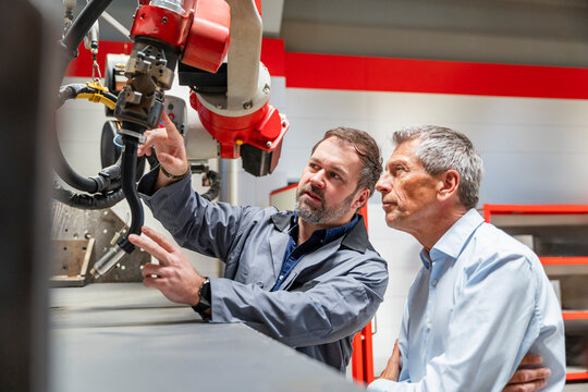 Engineer and manager inspect an industrial welding robot indoors