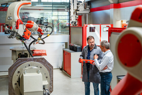 Engineer and manager inspecting industrial robot in factory