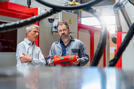 Manager and technician inspect industrial robot in factory