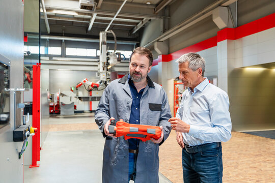 An engineer and a manager inspect a controller indoors