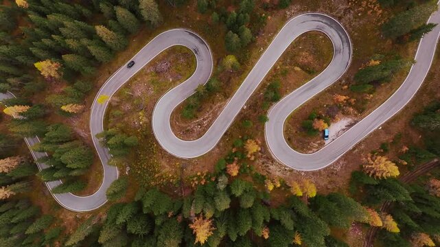 Giau Pass snake road in Italy, aerial top view of beautiful nature with bunch of green and yellow trees.