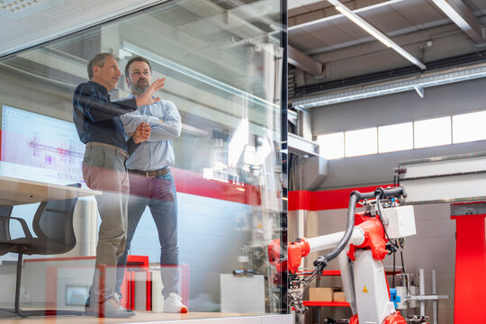 Manager and engineer plan production looking at industrial robot