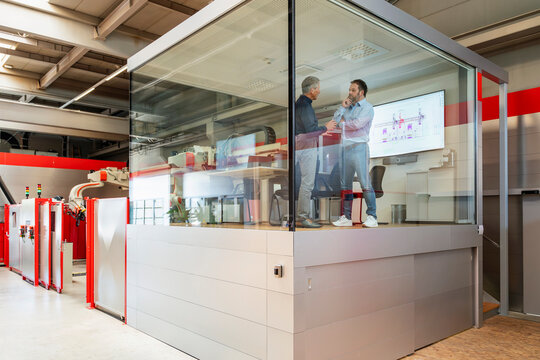 A manager and an engineer plan production in a glass factory office