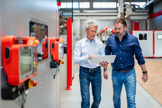 Engineers discussing factory production using a tablet