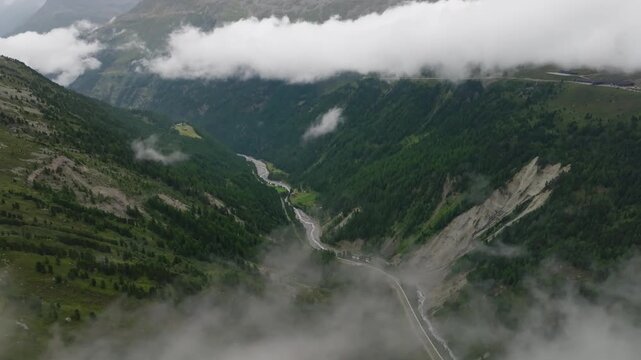 Aerial landscape of the Timmelsjoch mountain pass with clouds over rugged alpine peaks and deep valleys on the Austria Italy border for travel and tourism in Europe