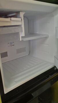 A Hand Opening an Empty and Clean Refrigerator Freezer Compartment with Purple Geometric Pattern Door