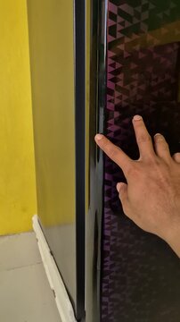 Interior View of a Clean Empty Refrigerator and a Hand Closing the Glossy Door with Purple Geometric Pattern