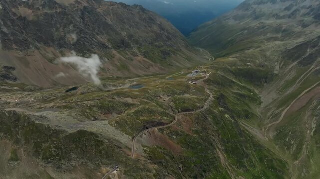 Aerial panorama of the Timmelsjoch High Alpine Road in Austria showcasing a tourist car driving between alpine mountain ranges and scenic European landscapes