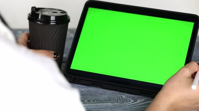 A woman's hand swipes through a tablet with a green screen
