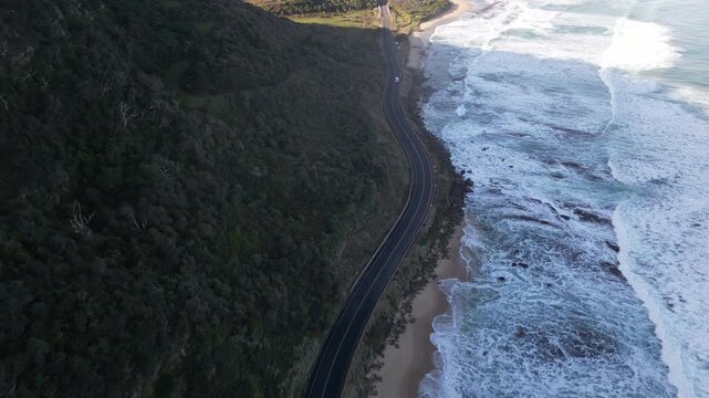 Aerial journey along Great Ocean Road Victoria Australia with scenic highway winding between mountains cliffs and the Southern Ocean coastline