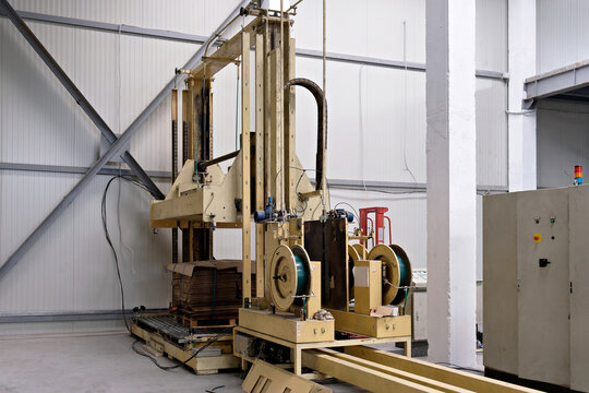 Automated industrial vertical strapping and packaging machine tool in a cardboard factory warehouse