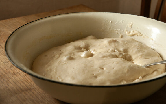 Rising yeast dough in a bowl, close up. Bubbles on the surface of the dough. Yeast dough making process. Homemade baking concept. Authentic traditional pastries making, realistic image