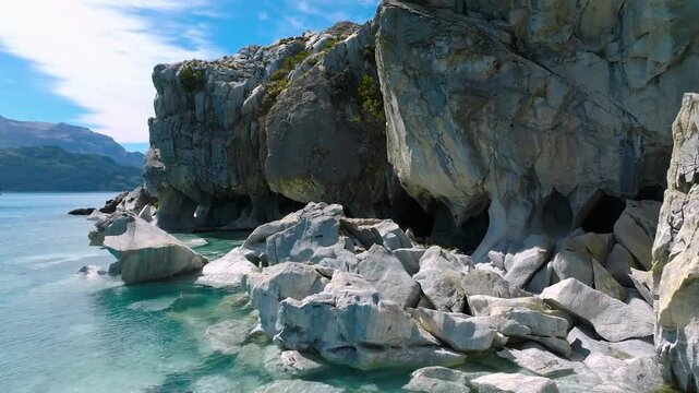 Marble cave formations beside turquoise lake water